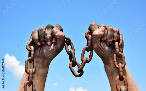 Two male hands holding a rusty metal chain