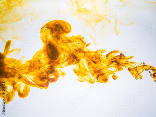Ink swirl in a water on white background. The paint splash in the water. Soft dissemination a droplets of colored ink in water close-up. Abstract background. Explosion of color splashes acrylic ink.
