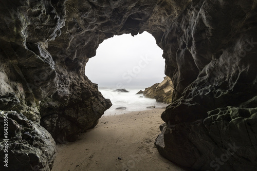 Sandy floor sea cave with motion blur water at Leo Carrillo State Beach in Malibu, California. 
