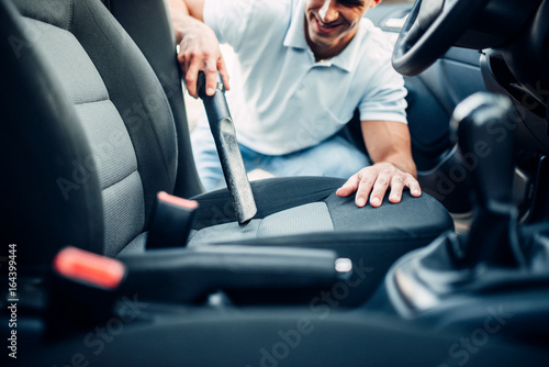 Man cleans car interior with vacuum cleaner