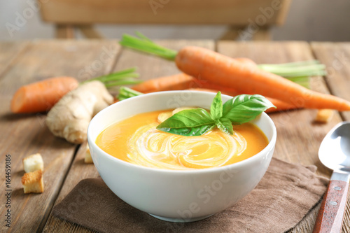 Delicious carrot soup on wooden table
