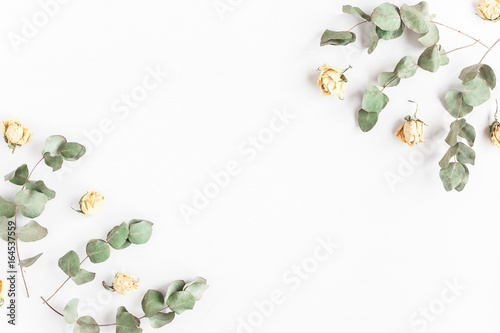 Flowers composition. Frame made of rose flowers and dried eucalyptus branches on white background. Flat lay, top view