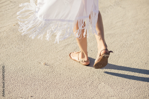 Female legs in sandals go on a desert sand