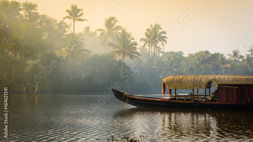 A traditional house boat is anchored on the shores of a fishing lake in Kerala's Backwaters, India.