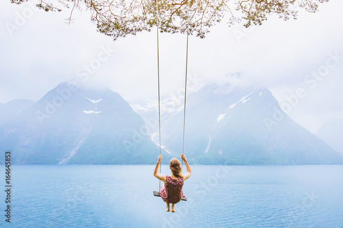 dream concept, beautiful young woman on the swing in fjord Norway, inspiring landscape