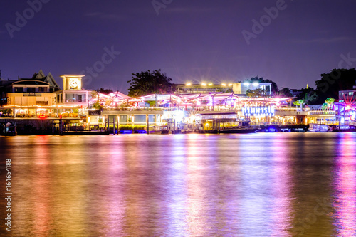 Bangkok, Thailand - JULY 17, 2017: Tha maharaj shopping mall and restaurant at night nearby the Grand Palace on the Chao Phraya River. Local boat at the pier, Bangkok, Thailand.