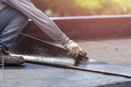 Group of worker installing tar foil on the rooftop of building. Waterproof system by gas and fire torching