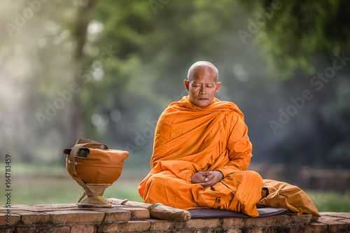 Asian monk meditating under a tree