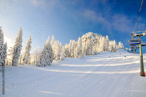 Stunning early morning shot of a ski slope and a chair lift near the Bavarian town of Garmisch Partenkirchen near Zugspitze mountain in Germany. Beautiful snow-covered trees in the background.