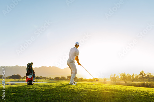 Professional male golfer taking shot on golf course