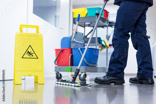 Worker janitor Mopping Floor In Office with trolley