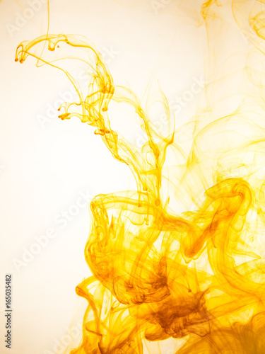 Ink swirl in a water on white background. The paint splash in the water. Soft dissemination a droplets of colored ink in water close-up. Abstract background. Explosion of color splashes acrylic ink.