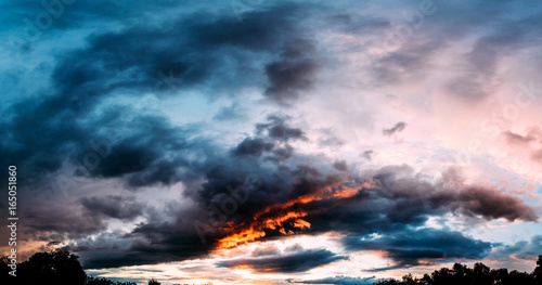 Panorama of dramatic gray, blue and orange sunset on beautiful sky, free space. Sky background on sunset with clouds