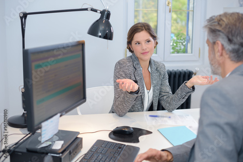 Businesswoman making questioning gesture to male colleague