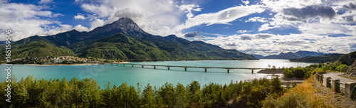 Panoramic view of Serre-Poncon Lake with Savines-le-Lac and its bridge with the Grand Morgon mountain peak in summer. Hautes-Alpes, Durance Valley, PACA Region, Southern French Alps, France