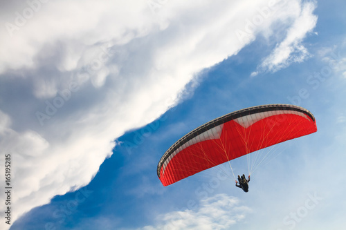 Red Paraglider against the Blue Sky with Clouds