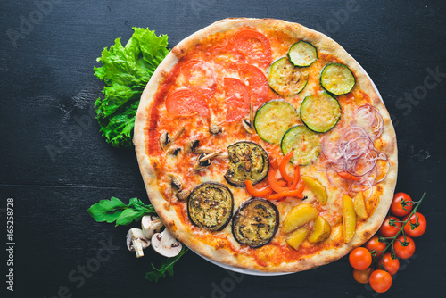 Pizza with vegetables and mozzarella. On a wooden background. Top view. Free space for your text.
