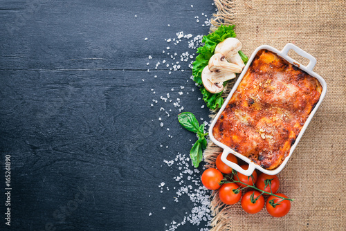 Lasagna with vegetables and cheese. On a wooden background. Top view. Free space for your text.