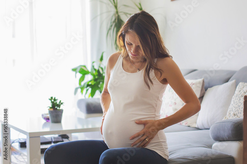 Young pregnant woman, having painful contraction, starting labor