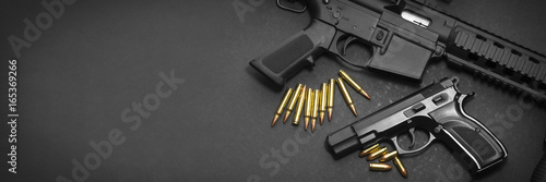 Handgun with rifle and ammunition on dark background with copy space