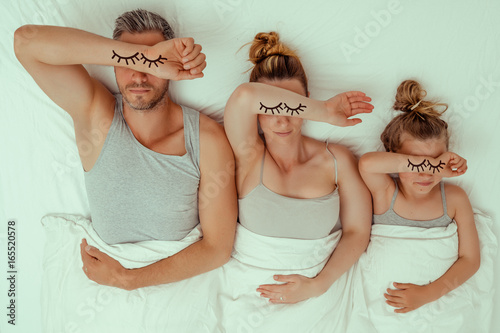 tired family in bed parents with daughter
