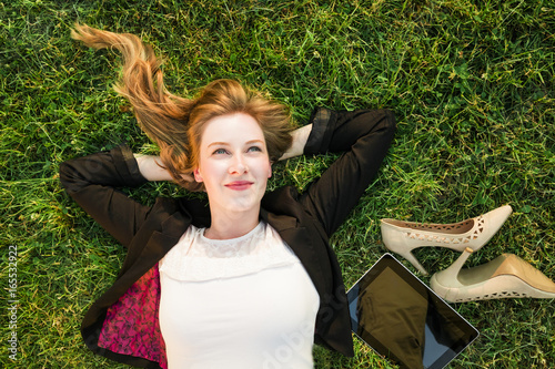 young independent woman relaxing on grass in park