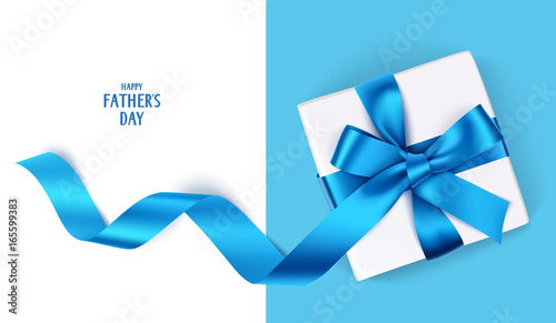 Decorative gift box with blue bow and long ribbon. Happy Father's Day text. Top view