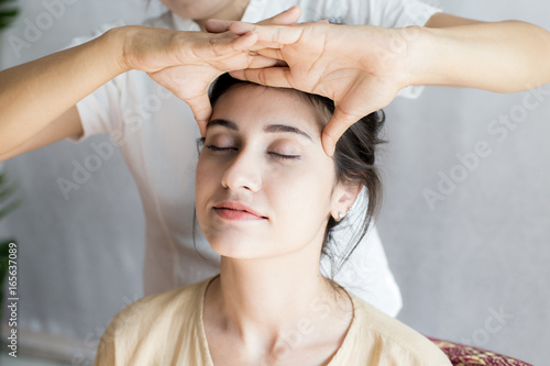 Beautiful young woman having head massage in spa salon. Woman with thai massage. Woman with relax emotion.