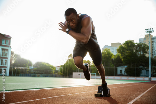 Young african runner running on racetrack
