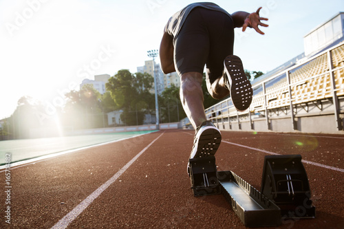 Back view of a young male athlete launching off the start line