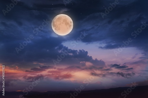 Glowing sunset and full moon . Beautiful cloudy sky. Cloudy abstract background. Sunset colors. 