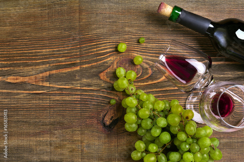 Two glasses, bottle of red wine and grape on a wooden table