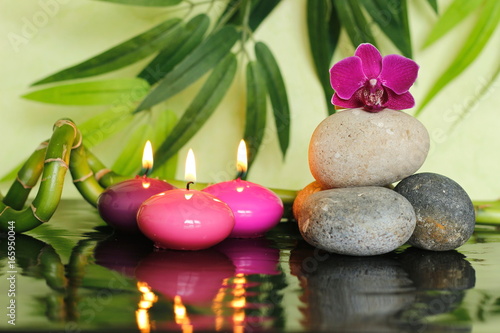 galets disposés en mode de vie zen sur la droite avec une orchidée au sommet et des bougies roses allumées