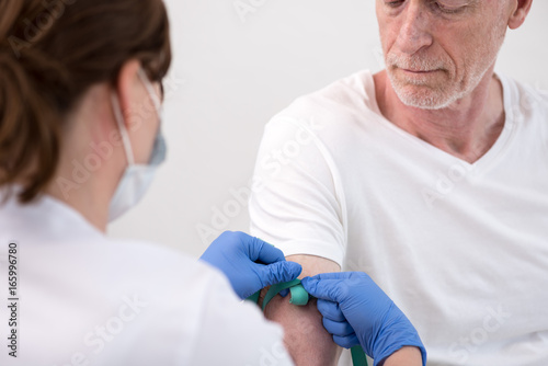 Putting a tourniquet on the arm of a patient