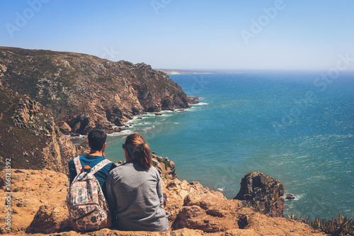 Couple in a cliff Atlantic ocean rocky coastline near from roca cape. Cascais, Sintra Portugal