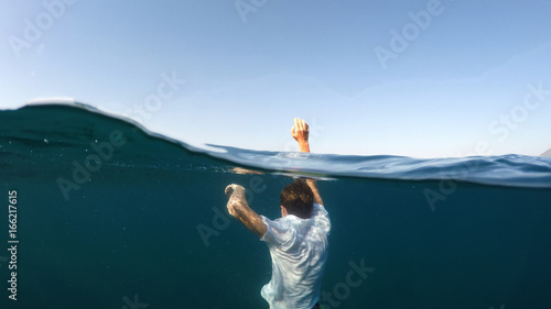 young man sinking into the sea