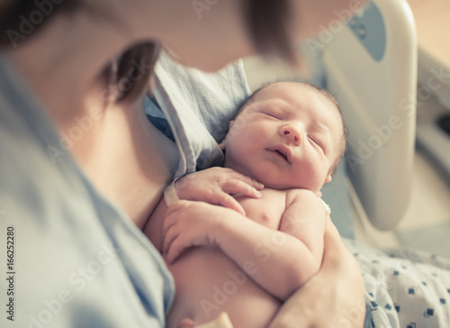 Parenting and new life concept. Mother holding newborn baby boy in her arms. 