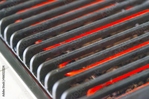 Hot red heaters and iron casted bars of an electric grill