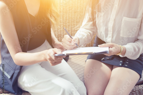 Businessperson Signing Contract about insurance, Two women writing with pen sign of modest agreements form In modern office, morning light, vintage color, success of business partners concept