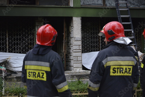 strażacy oglądający spalony budynek 