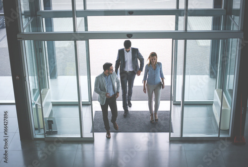 Business team gets to work. Three people entering the building.