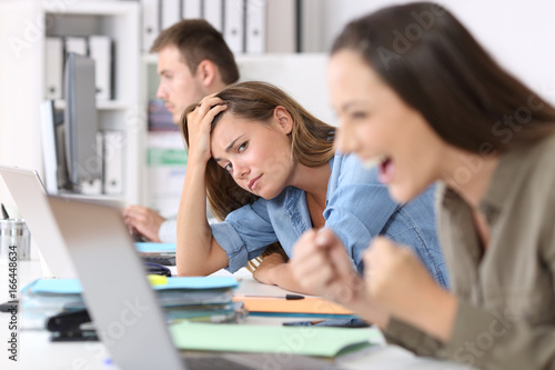 Worried worker beside successful one