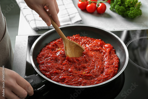 Woman preparing tomato sauce in frying pan