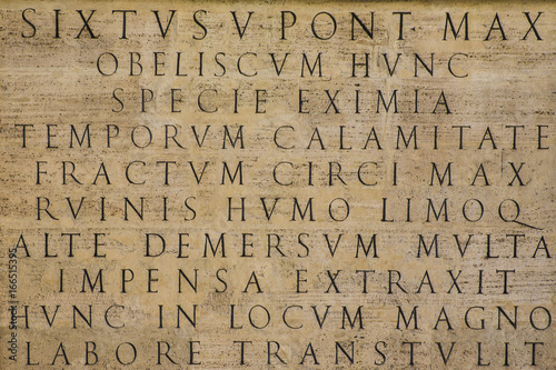 Dettaglio di un'iscrizione in latino e risalente agli antichi romani, ora su un obelisco situato a Roma. La base è di marmo e la scrittura traiana.