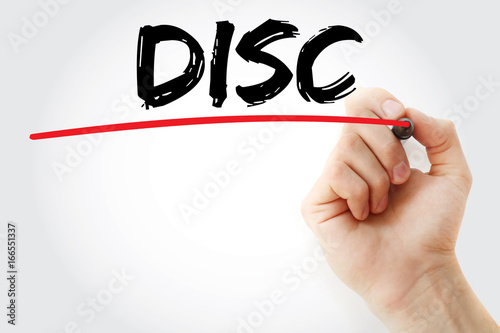 Hand writing DISC (Dominance, Influence, Steadiness, Conscientiousness acronym - personal assessment tool to improve work productivity) with marker, concept background