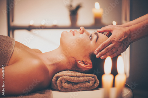 Spa facial massage. Brunette woman enjoying relaxing face massage in beauty spa salon