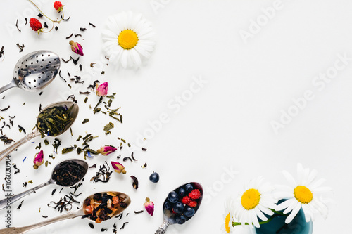 Variety of dried tea, dried herbal, green, black tea and fruit tea on vintage silverware tea spoons over white background with copy space / negative space. Table top view