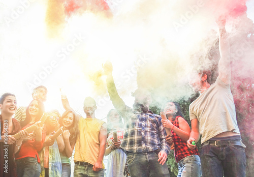 Happy friends using smoke bombs colors at party festival outdoor - Young students having fun and celebrating together - Youth and friendship concept - Main focus left guys faces - Contrast filter