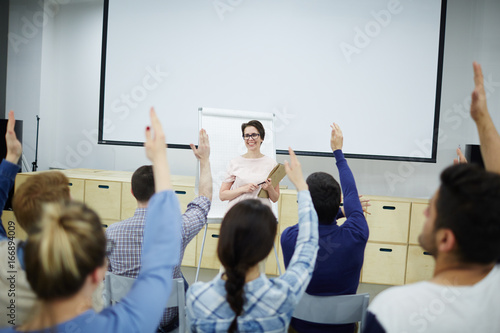 Business students raising hands to answer questions of coach