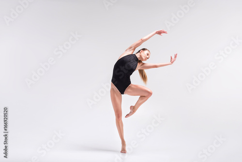 Serious young woman performing element of gymnastics choreography